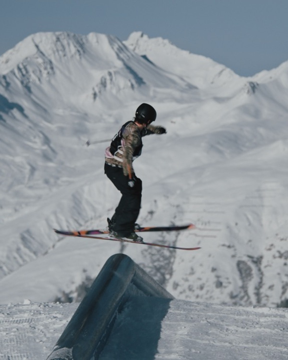 Freeskier macht einen Grab-Trick vor winterlichem Bergpanorama