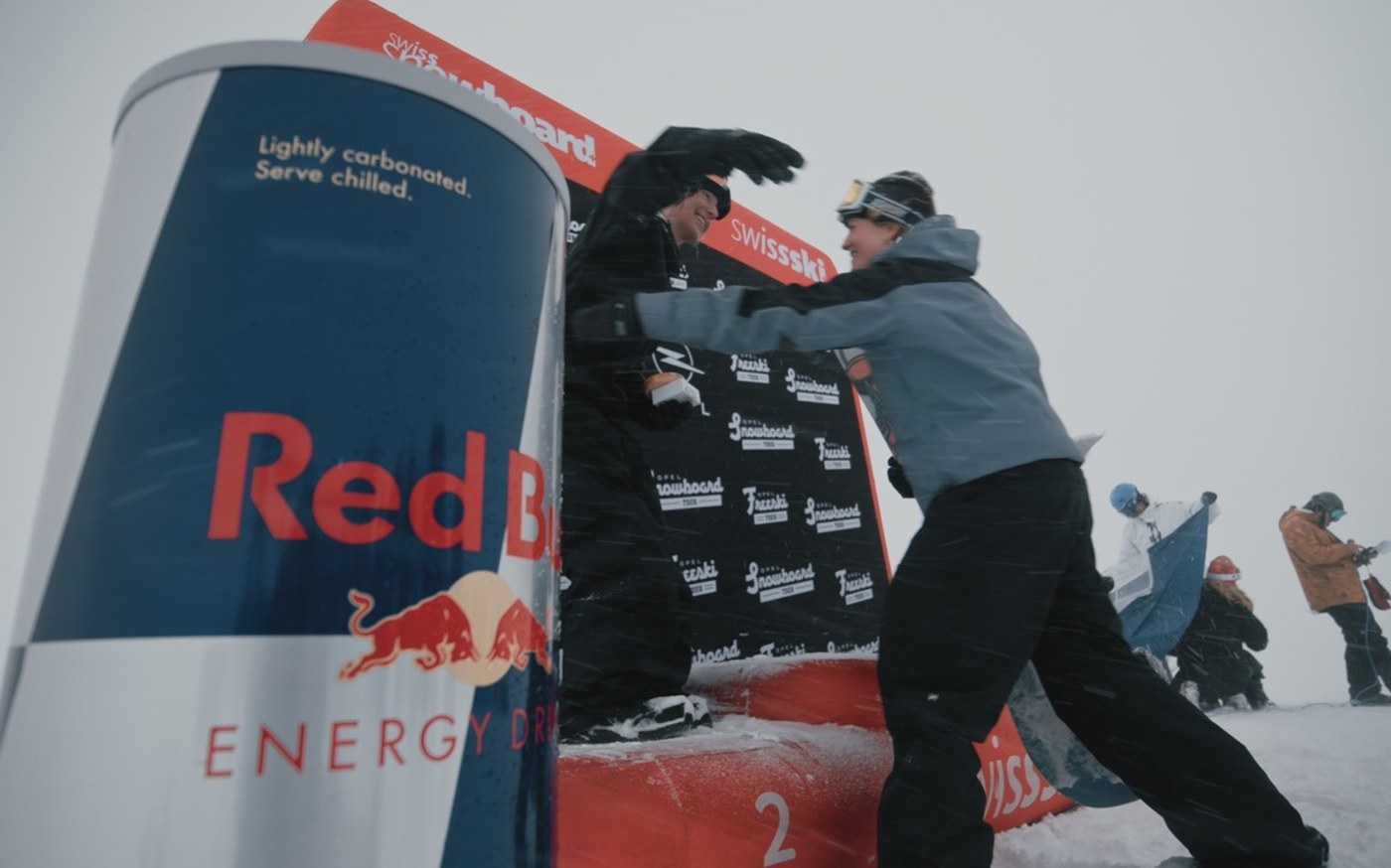 Athlet:innen feiern auf dem Podest, Red-Bull-Dose im Vordergrund