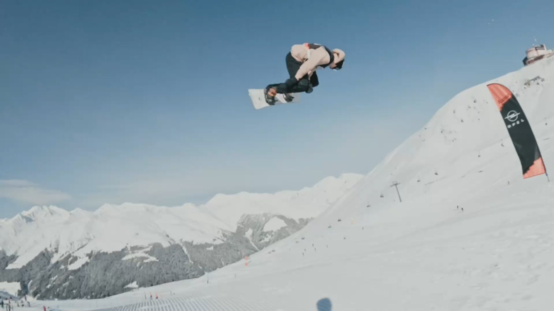 Snowboarder macht einen Trick-Grab hoch in der Luft über dem Snowpark Davos, Bergpanorama im Hintergrund