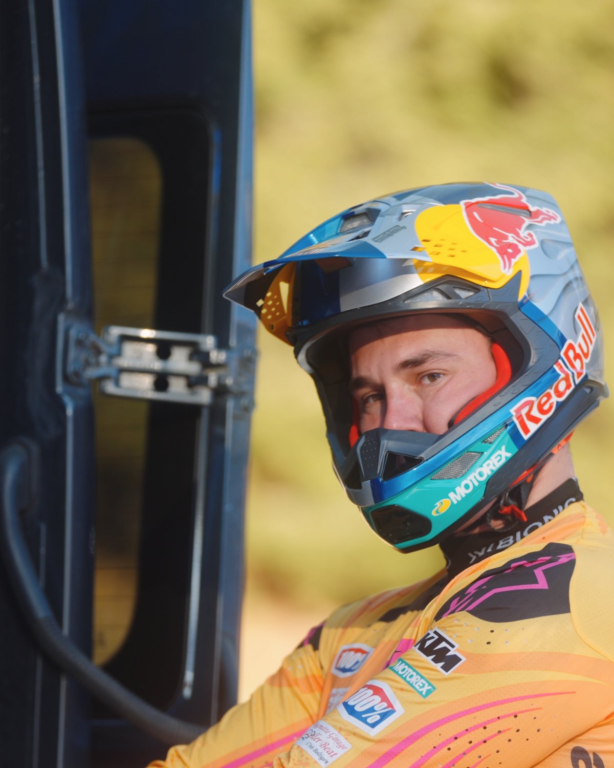 Porträt von Franjo von Allmen mit Red-Bull- und KTM-Motocross-Helm, goldenes Gegenlicht