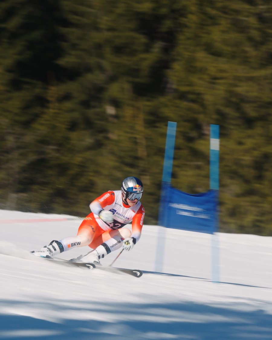 Franjo von Allmen fährt Slalom an einem Skitor vorbei, Bewegungsunschärfe, Red-Bull-Logo auf dem Helm