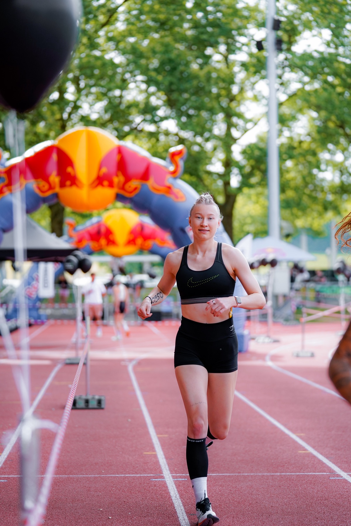 Athletin läuft ins Ziel, im Hintergrund der Red-Bull-Bogen