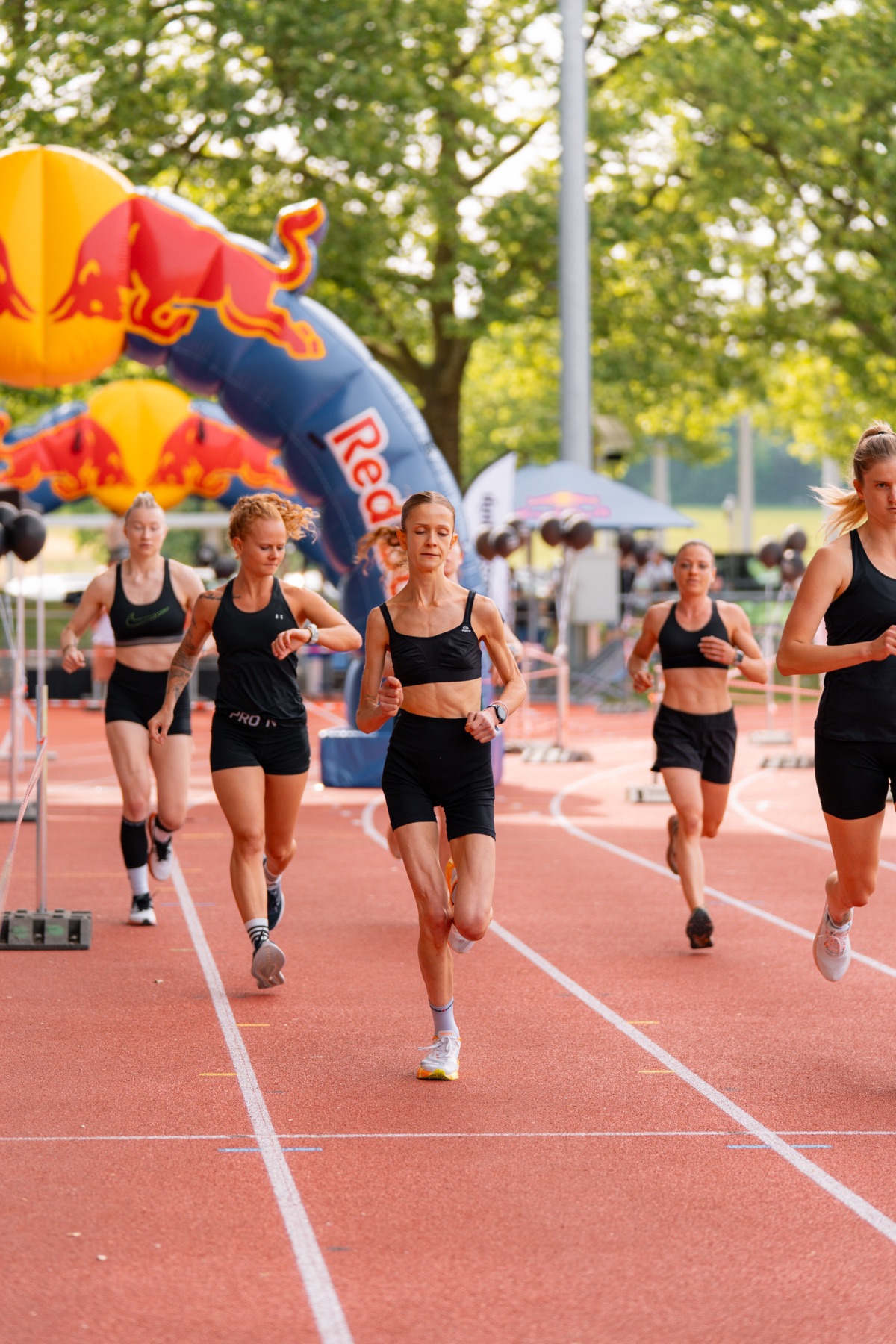 Gruppe Athletinnen läuft gemeinsam vor dem Red-Bull-Bogen
