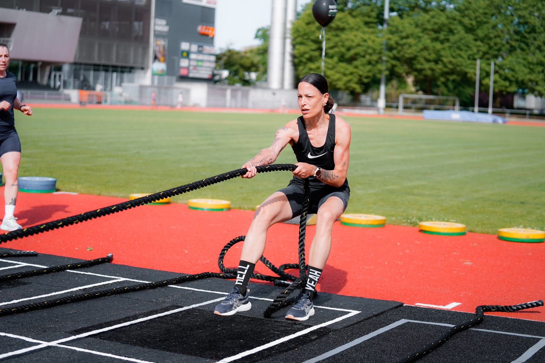 Athletin zieht ein Battle Rope auf dem Rasen