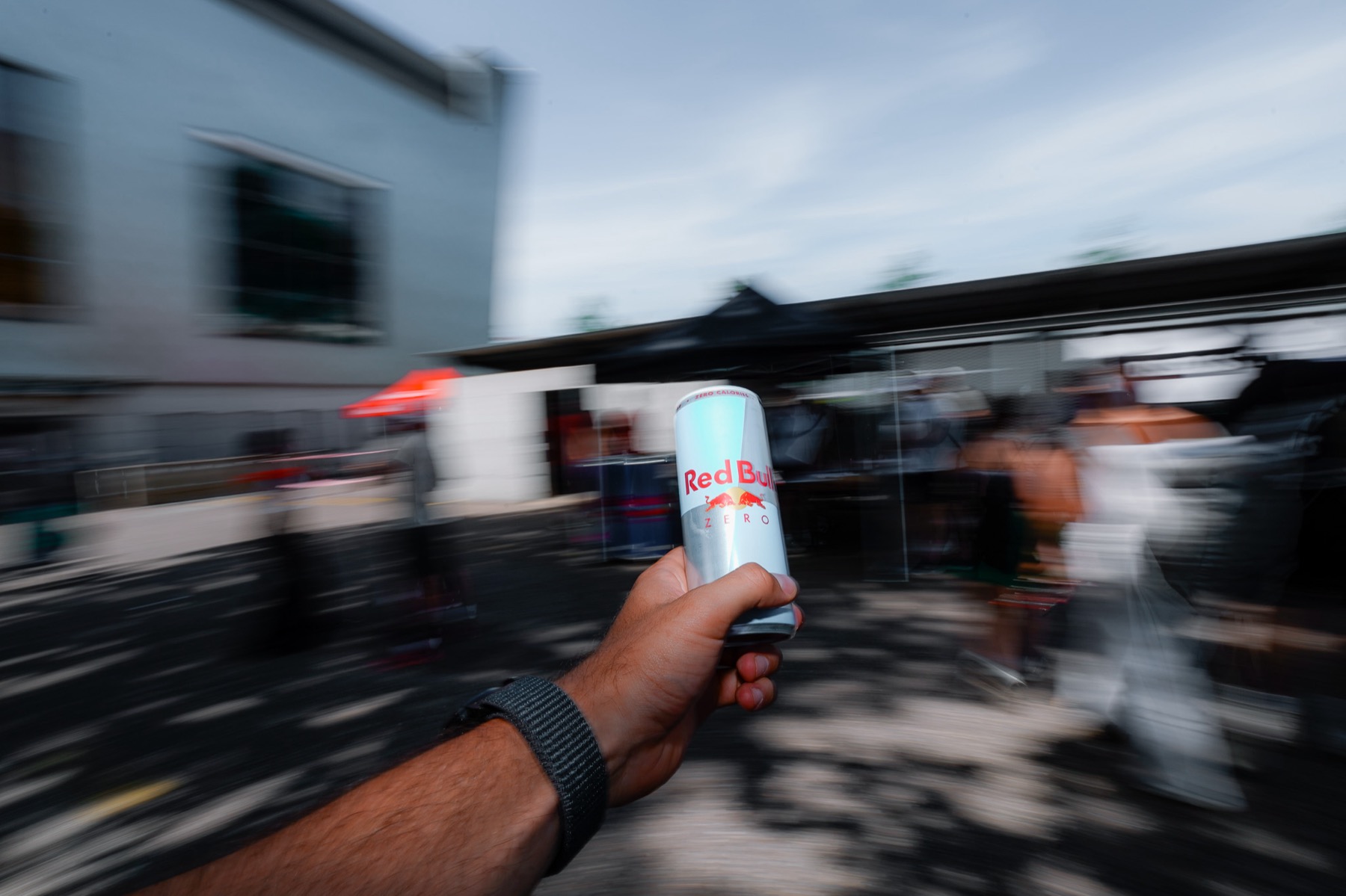 Athlet läuft mit einer Red-Bull-Dose in der Hand, Bewegungsunschärfe