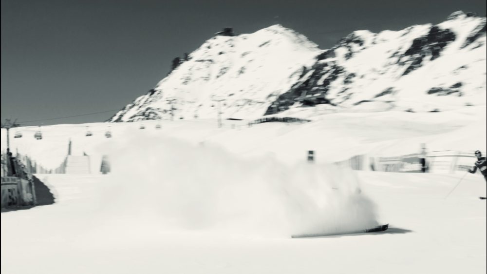 Pistenraupe wirbelt Schnee auf einem Berggipfel auf, monochrome Aufnahme