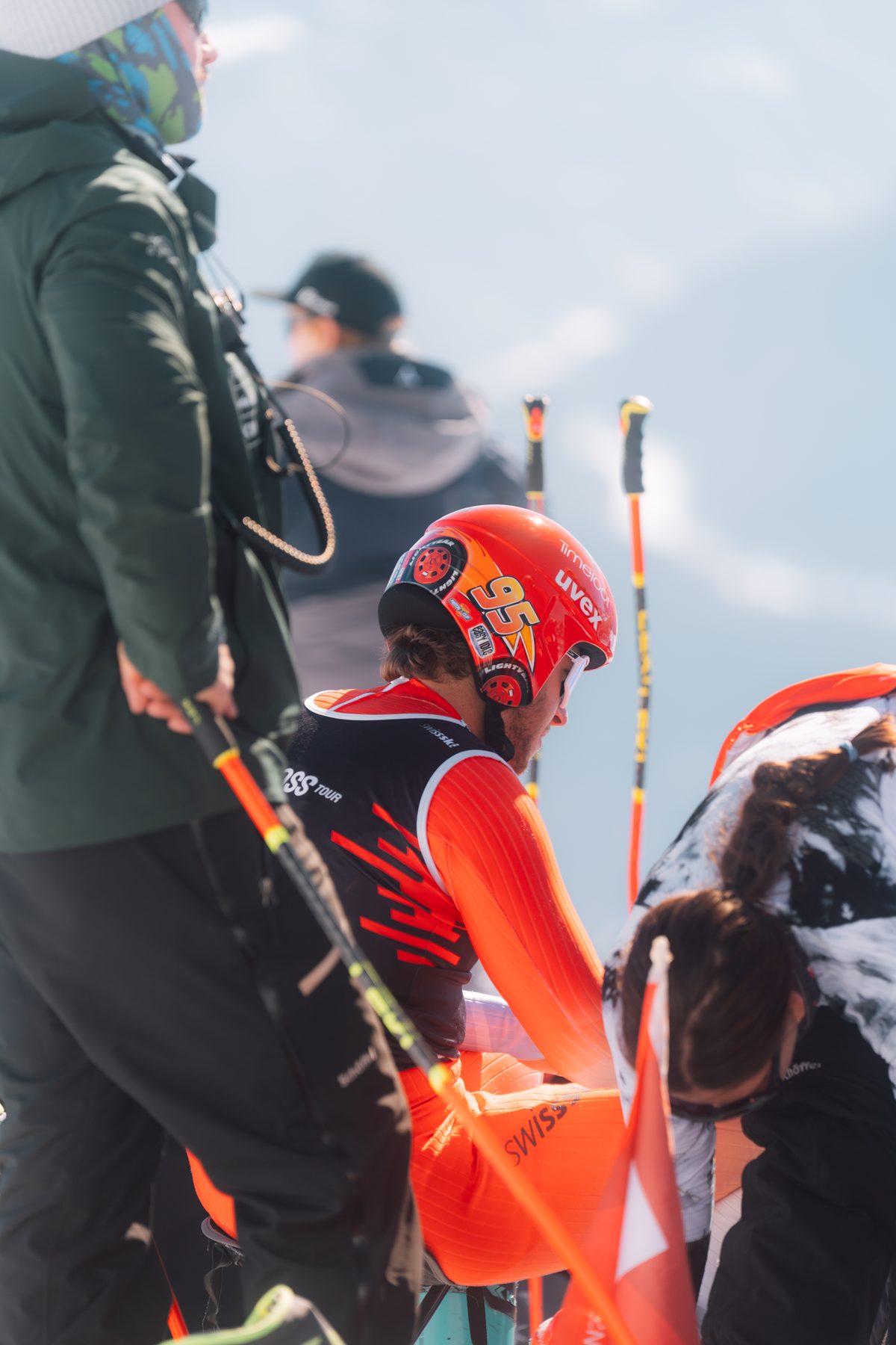 Athlet in orangem Rennanzug wird von Helfer betreut