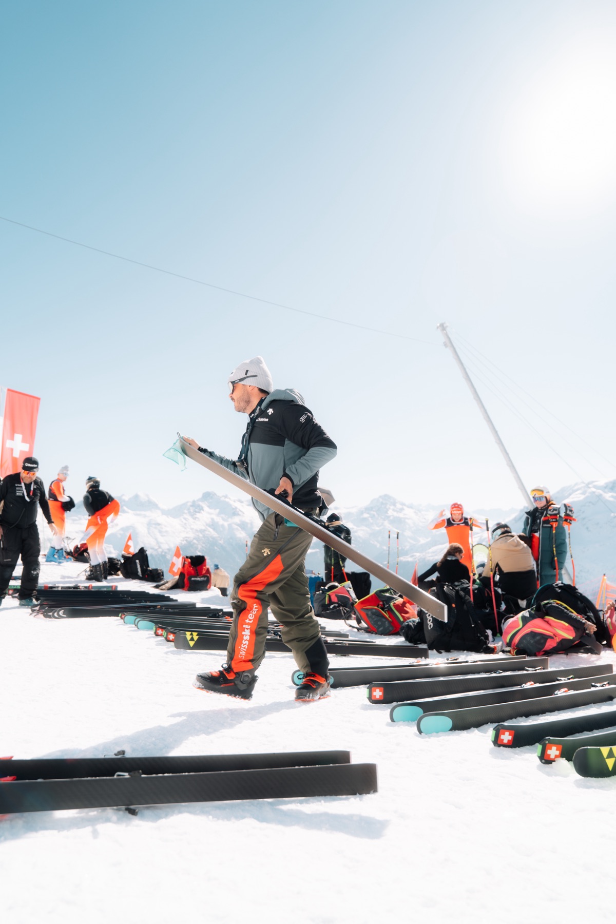 Betreuer trägt einen Ski über die aufgereihten Rennski am Start