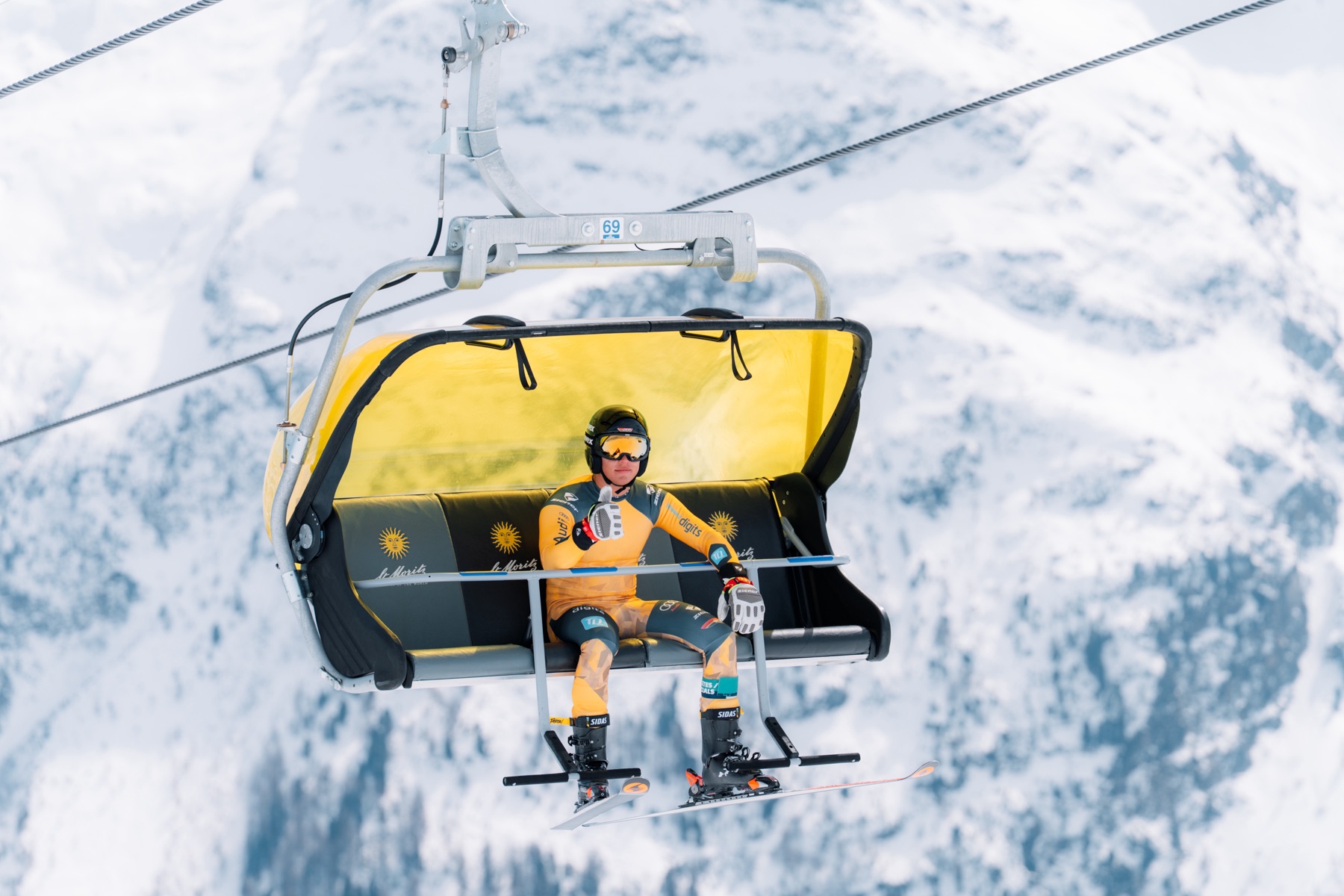 Athlet fährt mit dem Sessellift zurück zum Start, St. Moritz im Hintergrund