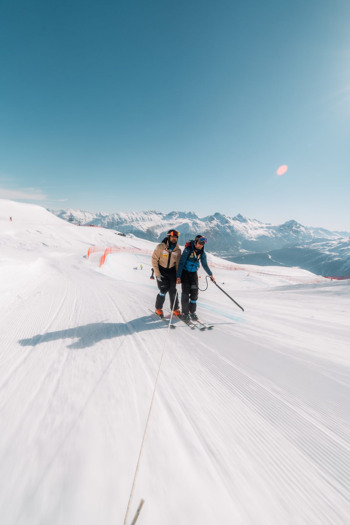 Athleten gehen die Rennstrecke im Schnee ab, Berge im Hintergrund